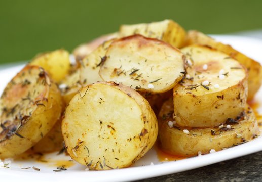 Close-up of plate with baked potatoes, spices, thyme and salt.