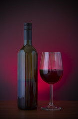Low key vignette image of red wine in glass with bottle