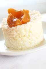 Sweet rice pudding with apricots on white plate.