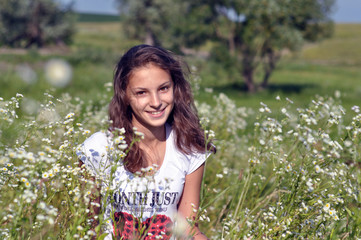 Beautiful happy girl smiling and relaxing in a field of daisies