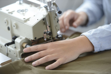 Closeup on dressmaker hand using sewing machine