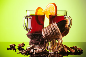 Mulled wine in two glasses and scarf on green