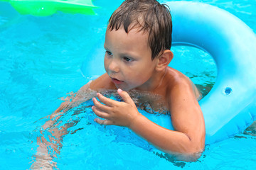 Preschool boy swims in pool on summer vacations