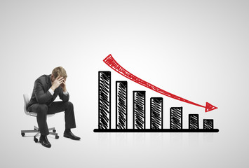 sad businessman sitting on chair with falling  chart