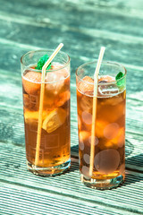 Iced tea with  lemon and mint on wooden table, outdo