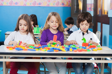 Children Playing With Construction Blocks In Classroom