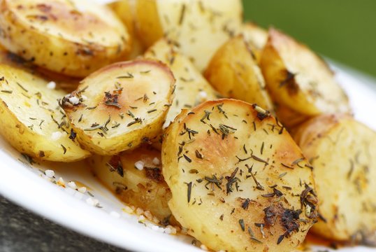 plate with baked potatoes with spices, thyme and salt.