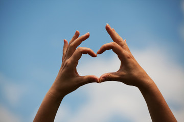 Love heart made with hands on blue sky