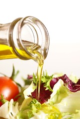 Close-up of bottle with pouring olive oil and vegetable salad