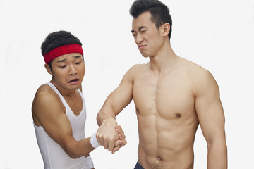 Fototapeta na wymiar One young man beating another at arm wrestling, studio shot