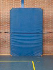 Large blue mat strapped to a brick wall
