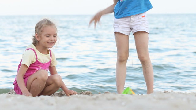 Little girls playing and droping sand on the beach