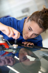 Young student in bodywork changing car windshield - obrazy, fototapety, plakaty
