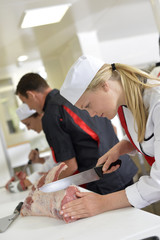 Girl cutting meat during butcher training course