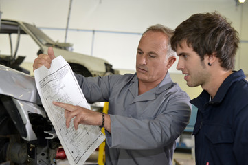 Teacher with coachbuidling student in repairshop