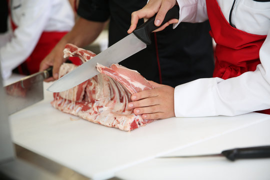 Closeup of ribs being cut in butcher kitchen