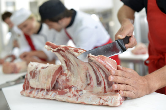 Closeup of ribs being cut in butcher kitchen