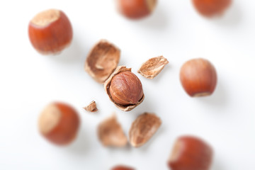 peeled hazelnut among unpeeled, isolated on white background
