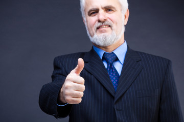 Studio shot of  business man showing thumb up sign on the dark b