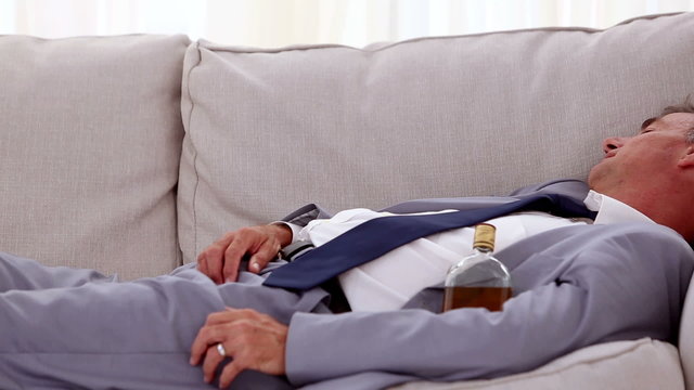 Alcoholic businessman lying and sleeping on sofa