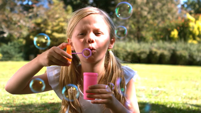 Young girl blowing into a bubble wand