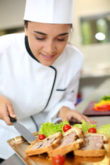 Portrait of beautiful young caterer preparing food tray