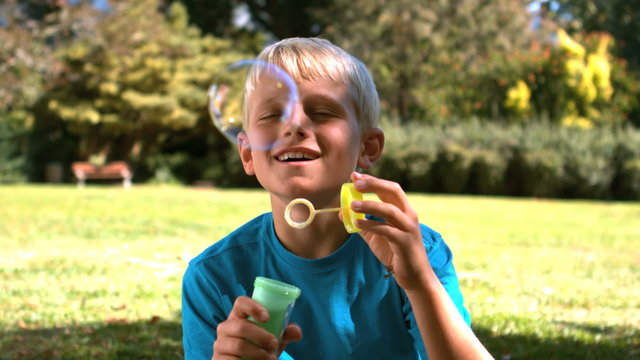 Young boy blowing into a bubble wand
