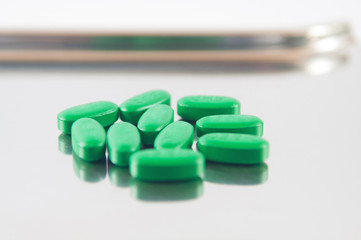 Closed up green tablet on metal dispensing tray