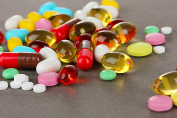 Assortment of pills, tablets and capsules on grey background