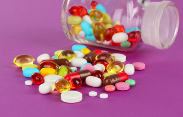 Assortment of pills, tablets and capsules on purple background