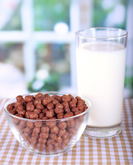 Delicious and healthy cereal in bowl with milk on table in room