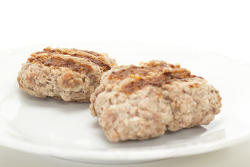 Two grilled meatballs on white dish