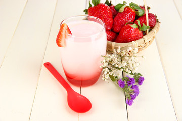 Delicious strawberry yogurt in glass on wooden table close-up