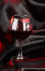 Glass of wine with lipstick imprint on black satin background