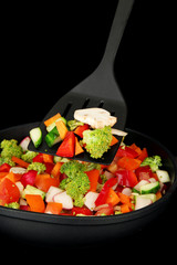 Vegetable ragout in pan, isolated on black