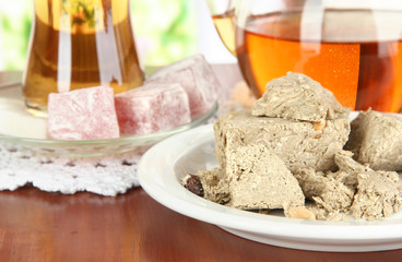 Tasty halva with tea on table in room