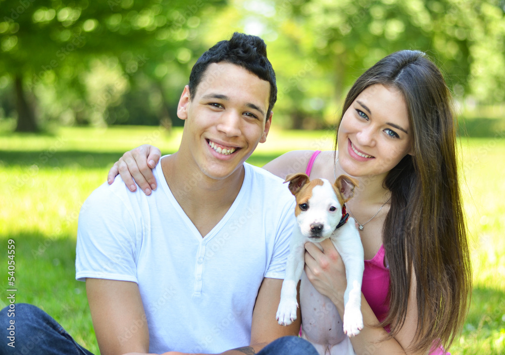 Wall mural Happy couple with puppy dog at park