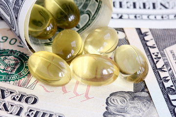 Gel capsules pouring out of rolled dollar bills