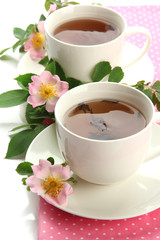 Cups of herbal tea with hip rose flowers, isolated on white