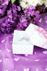 Beautiful box with wedding ring on purple background