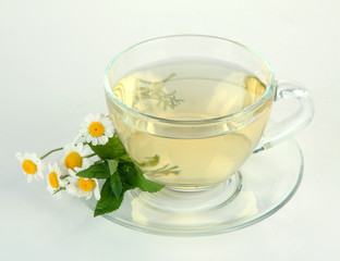 Cup of herbal tea with wild camomiles and mint, isolated