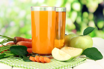 Glasses of juice, apples and carrots