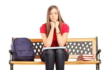 Unhappy female student sitting on a wooden bench