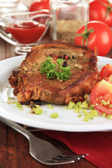 Piece of fried meat on plate on wooden table close-up