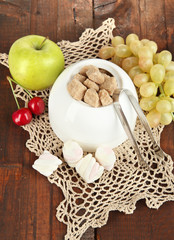 Unrefined sugar in white sugar bowl on wooden background