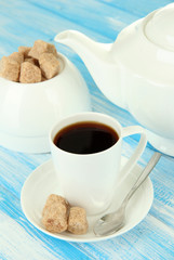 Cup of coffee, teapot and sugar-bowl on color wooden background