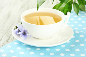 Cup of tea with chicory, on wooden background