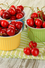 Cherry berries in bowls on wooden table close up