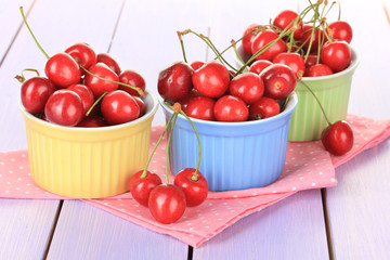 Cherry berries in bowls on wooden table close up