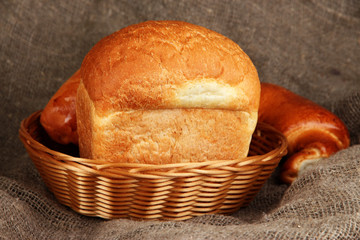 Baked bread in wicker basket on burlap background